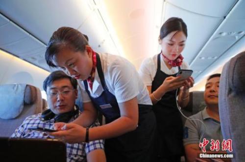 資料圖：乘務(wù)員們?cè)诳团搩?nèi)為旅客調(diào)試機(jī)上上網(wǎng)功能。<a target='_blank' ><p  align=