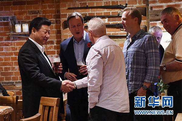 這是習近平與卡梅倫飲啤酒，并同當?shù)孛癖娊徽?。新華社記者 饒愛民 攝
